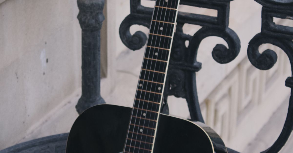 Guitar String Railing A black guitar sitting on a black railing · Free Stock Photo
