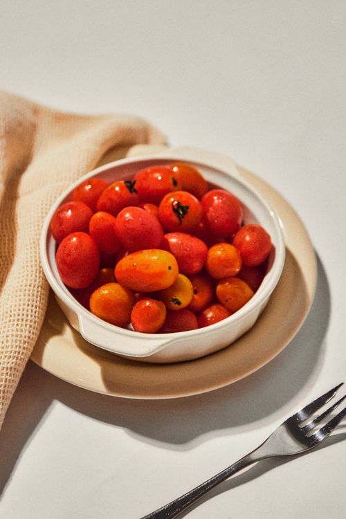 Free Juicy cherry tomatoes in a white bowl on a neutral background, ideal for healthy eating concepts. Stock Photo