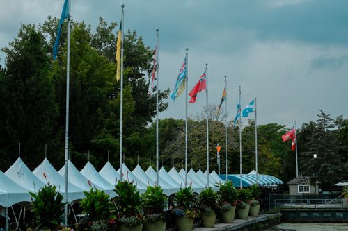 Free Multiple flags on poles against tents in a park, Toronto, showcasing diverse cultures. Stock Photo