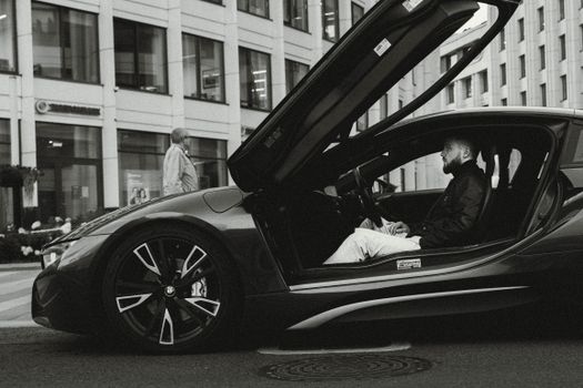 Man in a BMW i8 sports car in Moscow cityscape, showcasing modern urban lifestyle.