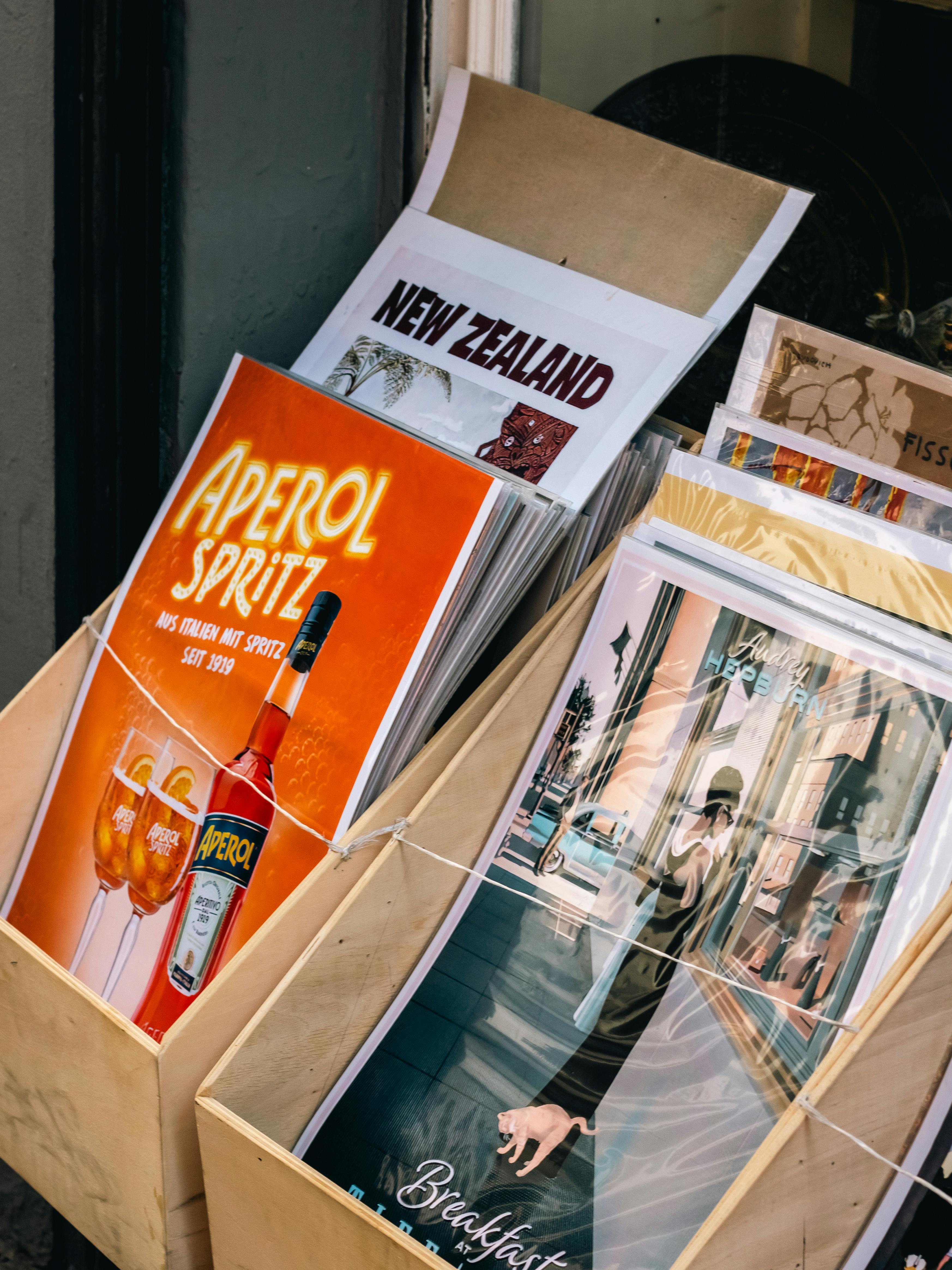 Assorted vintage posters in a wooden stand featuring travel and beverage themes.
