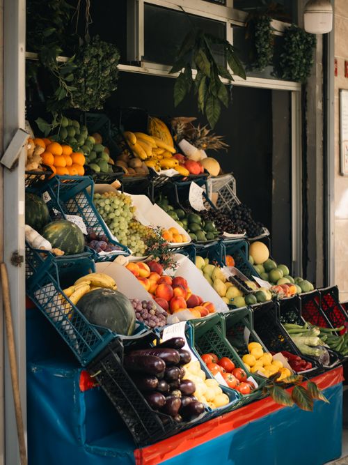 Free A vibrant array of fresh fruits and vegetables displayed at an outdoor market stall. Stock Photo