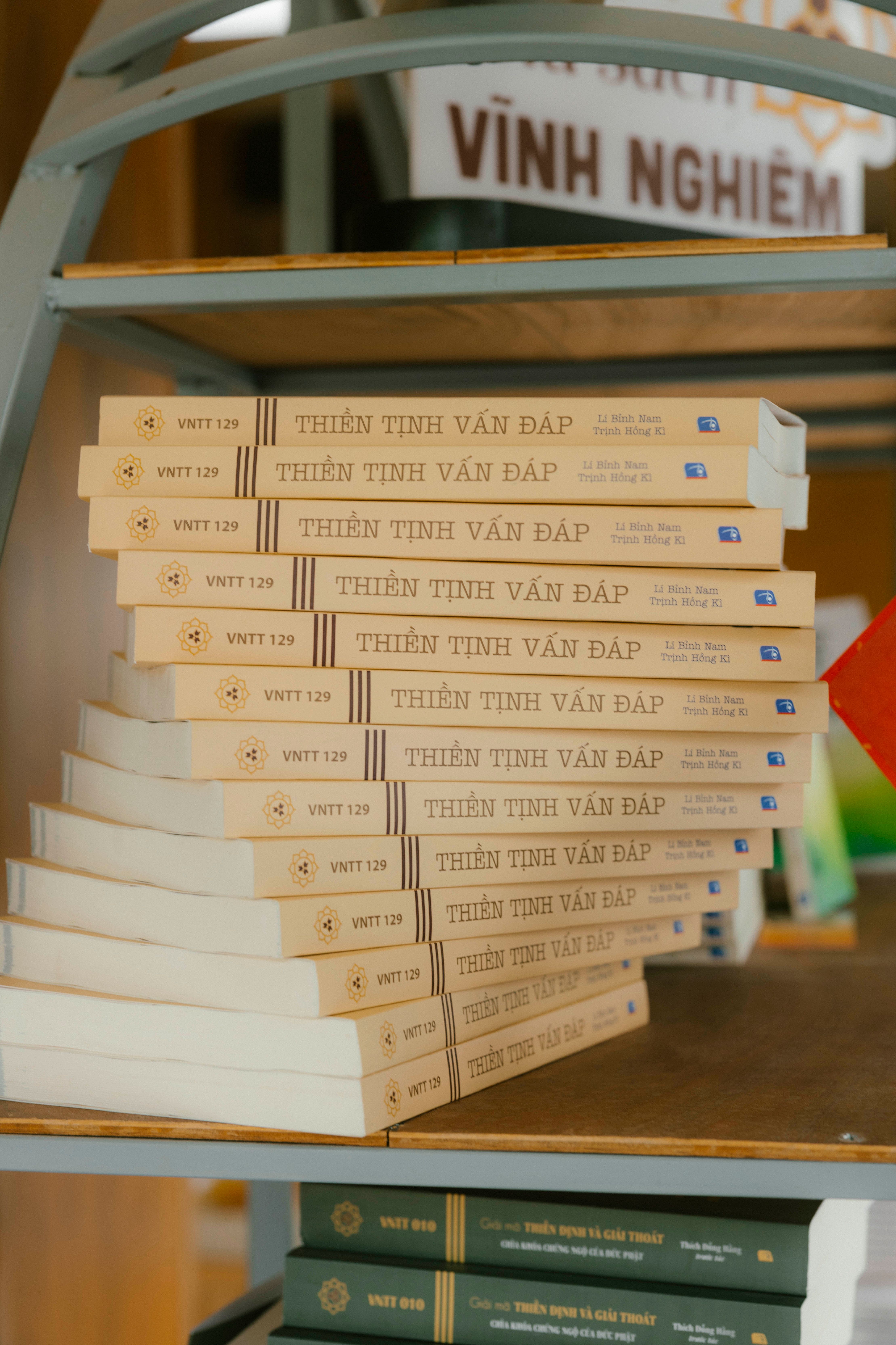Stack of books titled 'Thien Tinh Van Dap' on a library shelf in Vinh Nghiem Temple.