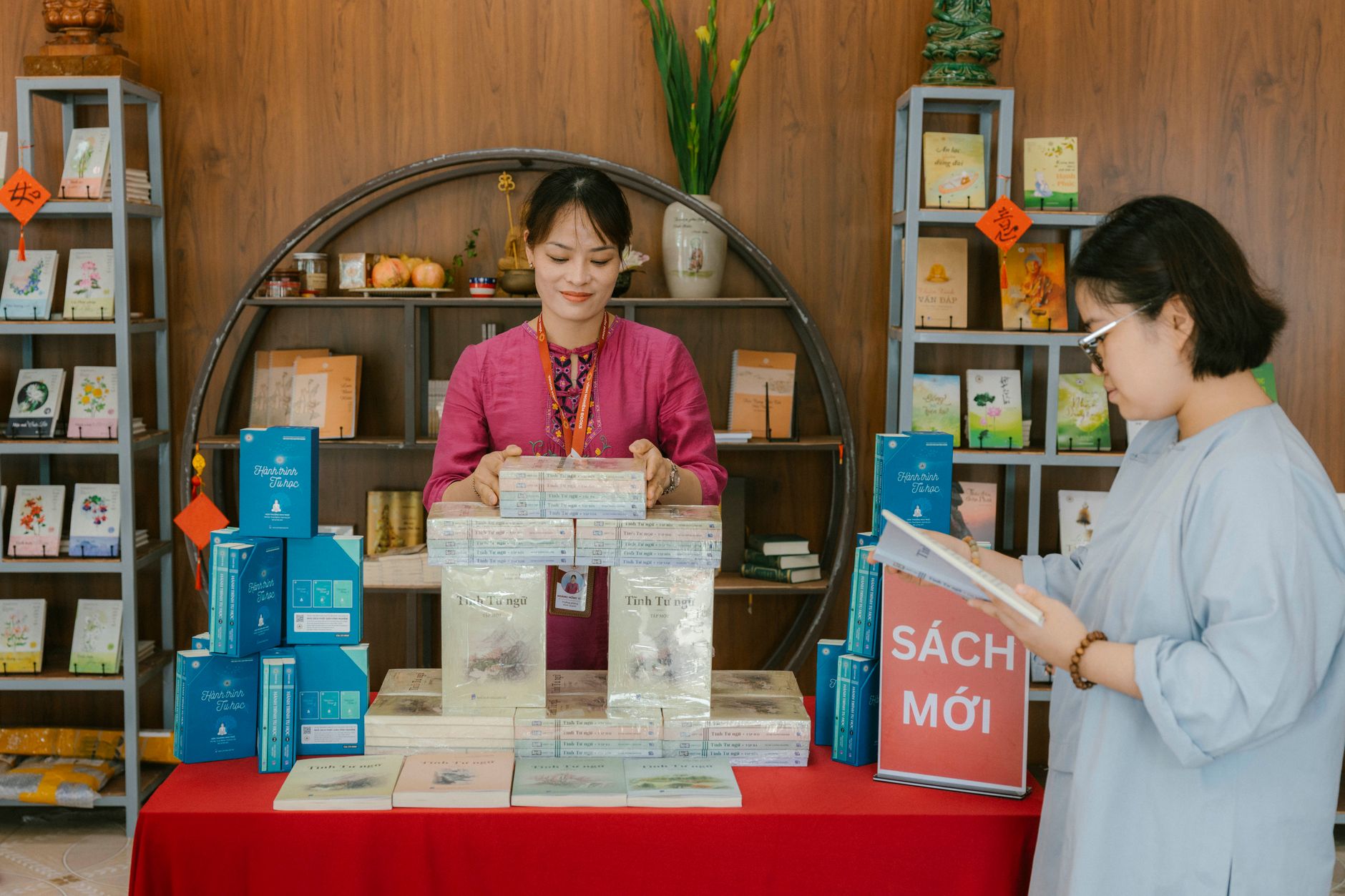 Two women interacting in a bookstore, arranging books on shelves.