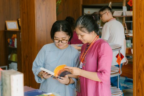 Free Two women engaged in reading and discussing books inside a modern library setting. Stock Photo