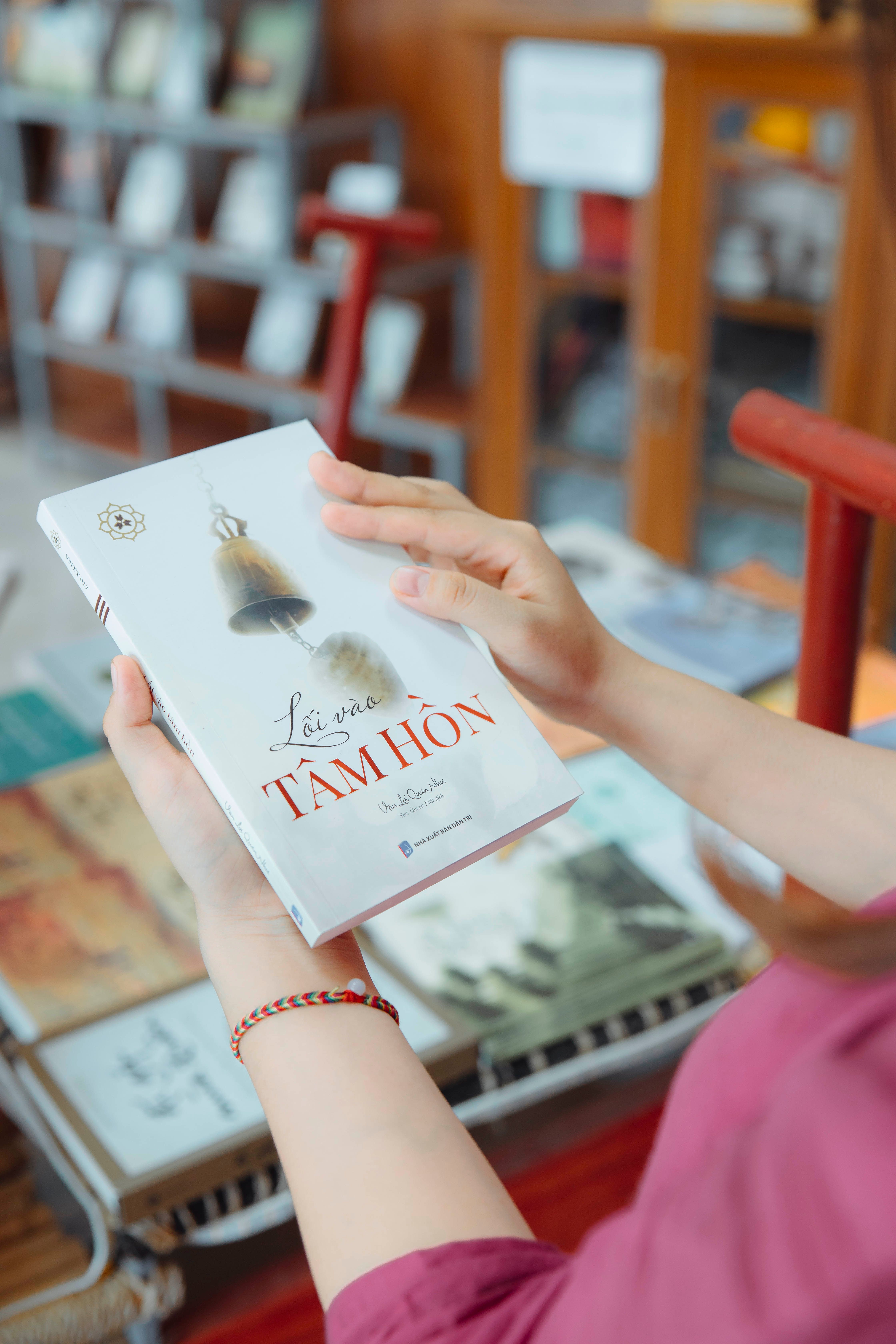 A person holding a book titled 'Lời Ru Tâm Hồn' in a cozy indoor setting.