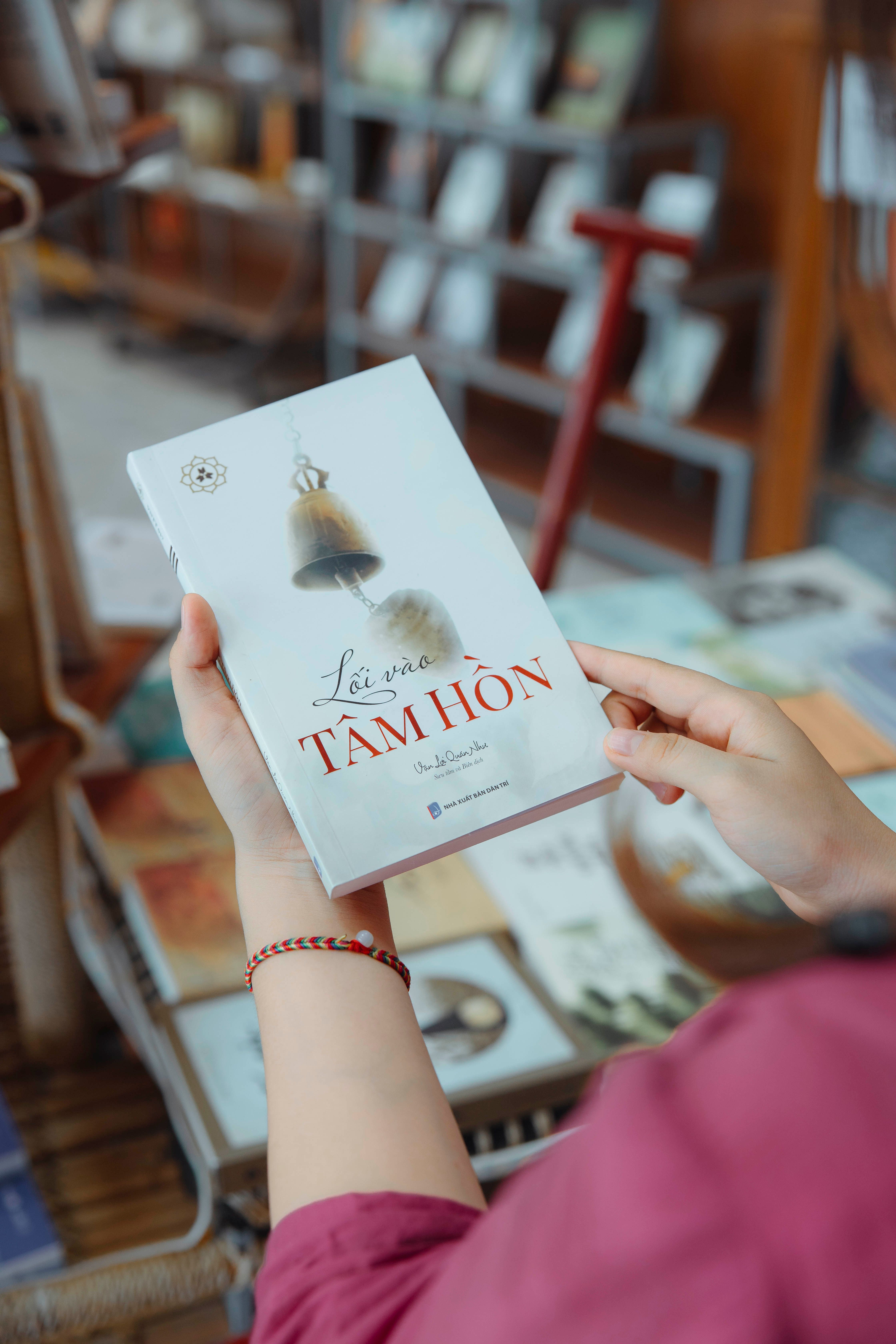 Close-up of hands holding a Vietnamese book in a bookstore setting.