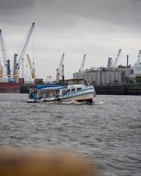 A bustling scene of Hamburg Harbor featuring boats and cranes on a cloudy day, showcasing maritime activity.