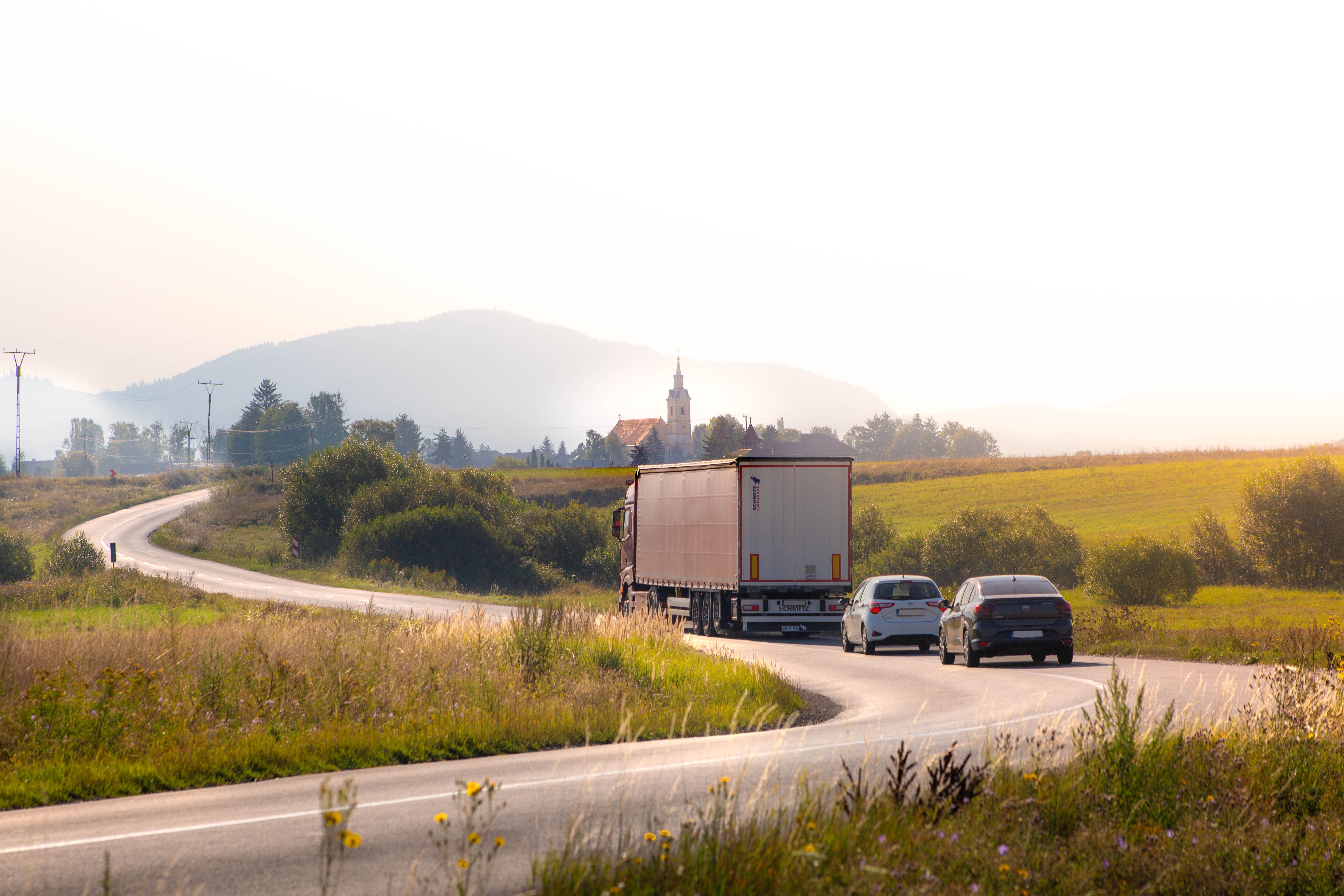 A truck driving down a road with a sun setting in the background · Free ...