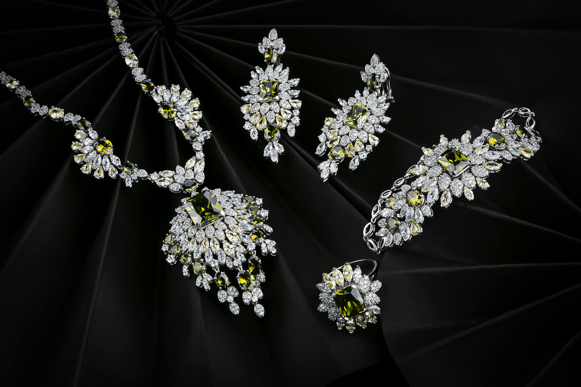 Luxurious set of diamond and emerald jewelry on a black background, highlighting elegance.