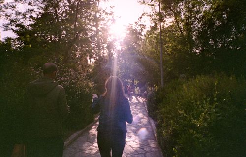 Free A couple walks through a sunlit, misty park trail in Amman, capturing a serene morning scene. Stock Photo