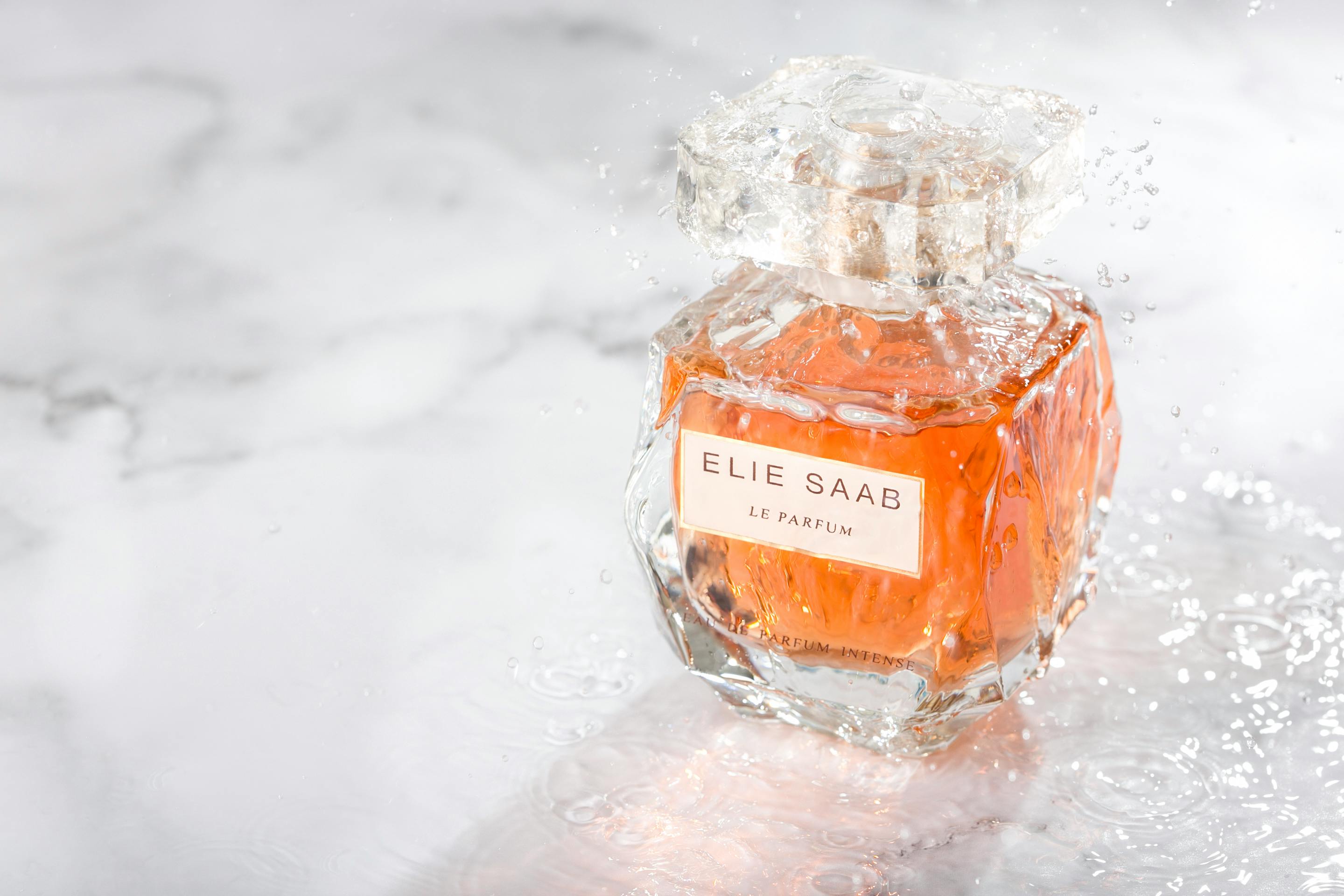 Close-up of a perfume bottle with splashing water, showcasing elegance and luxury.
