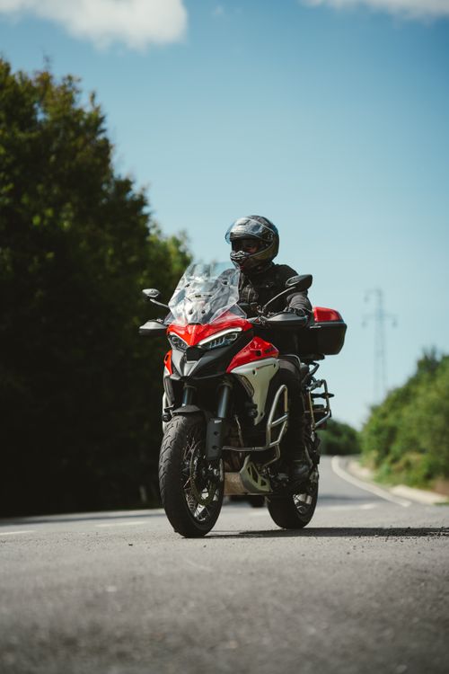 Free Motorcyclist wearing helmet riding a red motorcycle on a sunny open road. Stock Photo