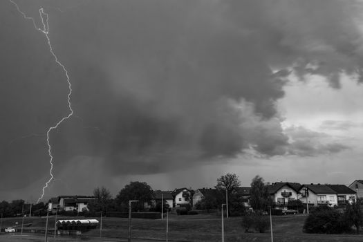 Monochrome image capturing a dramatic lightning strike during a thunderstorm over a neighborhood.