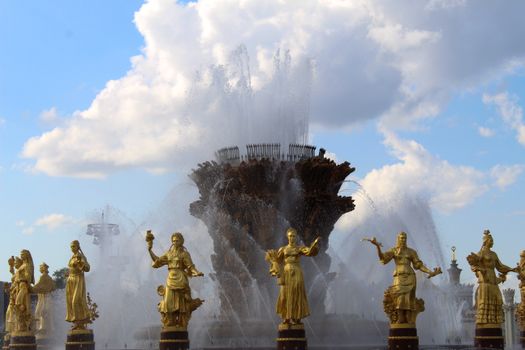 Stunning fountain with golden statues under a blue sky at VDNKh, showcasing artistic craftsmanship.