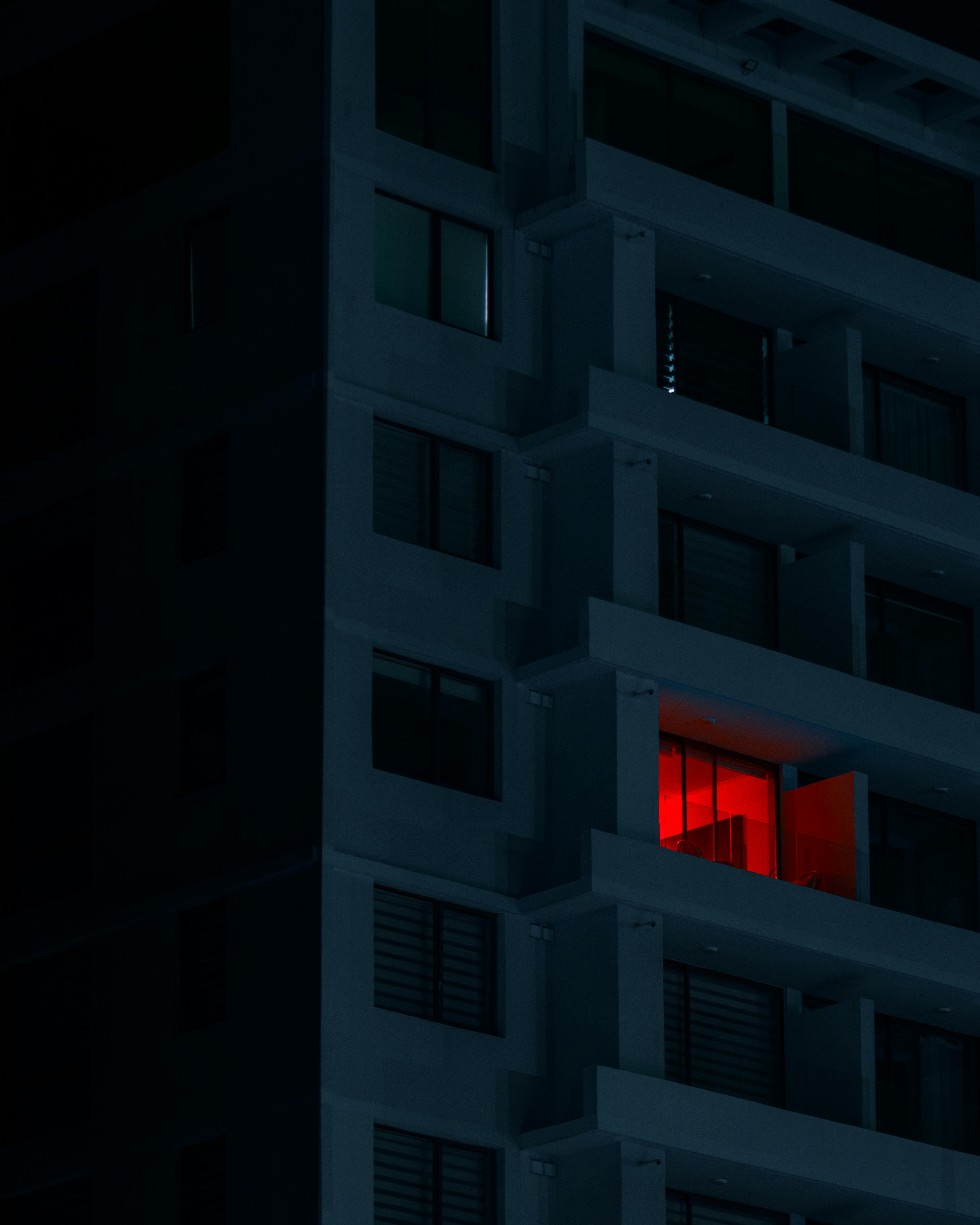 Night shot of a modern apartment building with a striking red-lit balcony in Chillán, Chile.