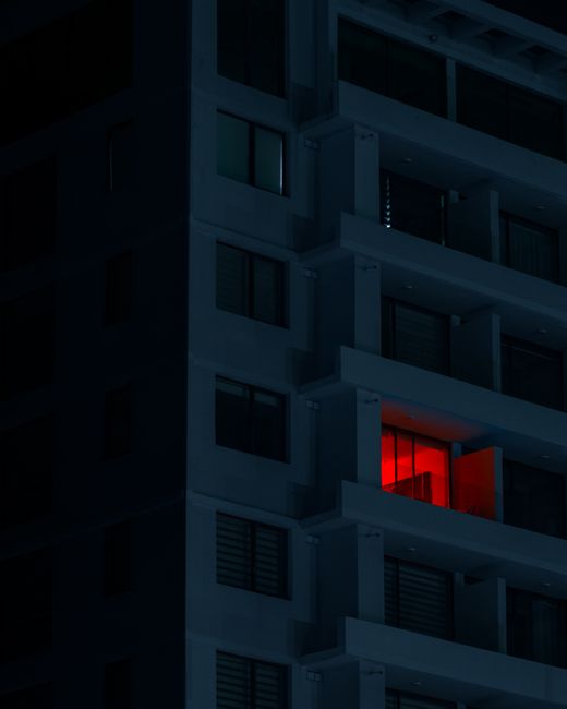 Night shot of a modern apartment building with a striking red-lit balcony in Chillán, Chile.