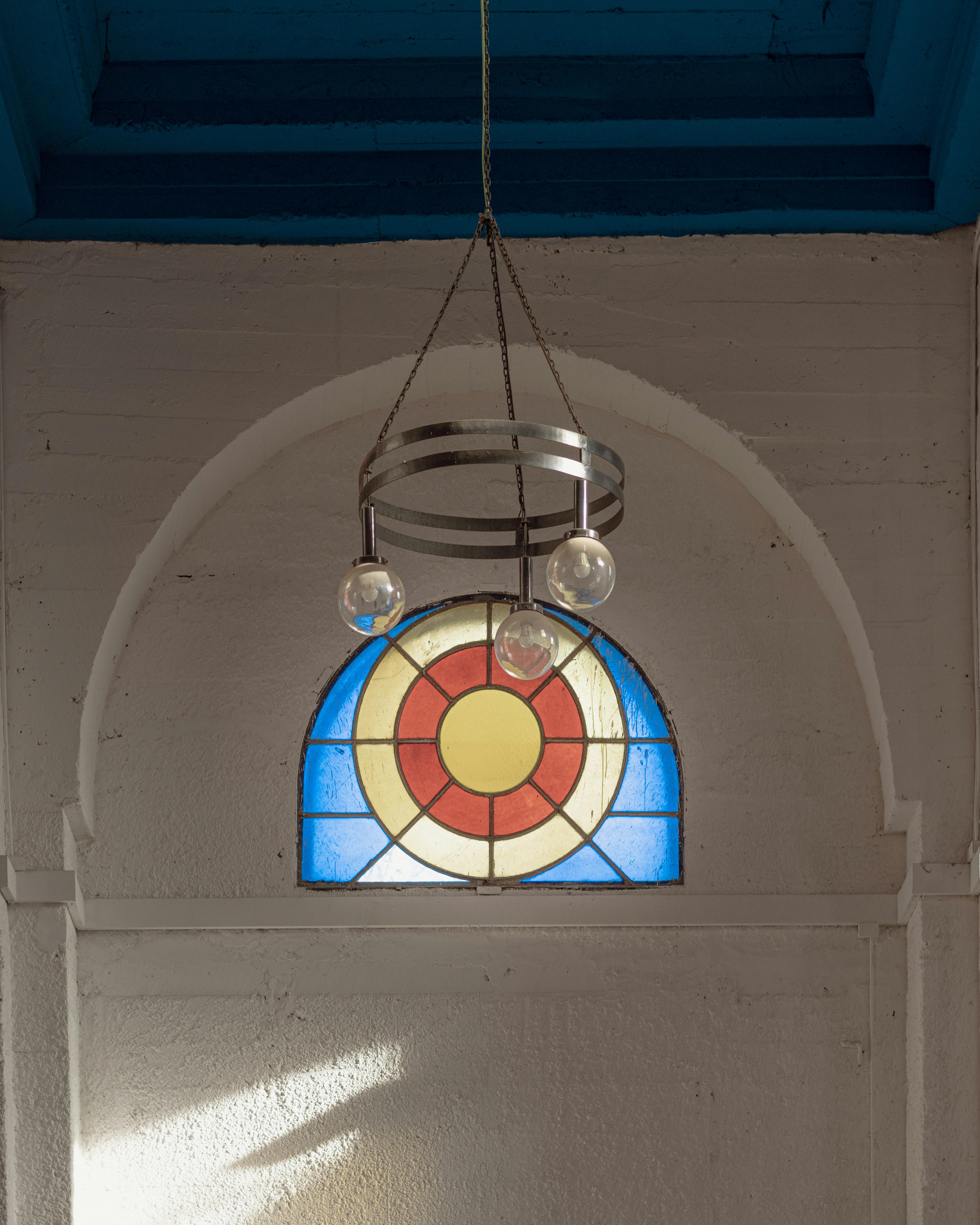 Vibrant stained glass window in a rustic archway, casting colorful reflections indoors.