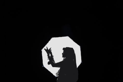 Free Artistic silhouette of a bride in traditional attire against a striking backlit setup. Stock Photo