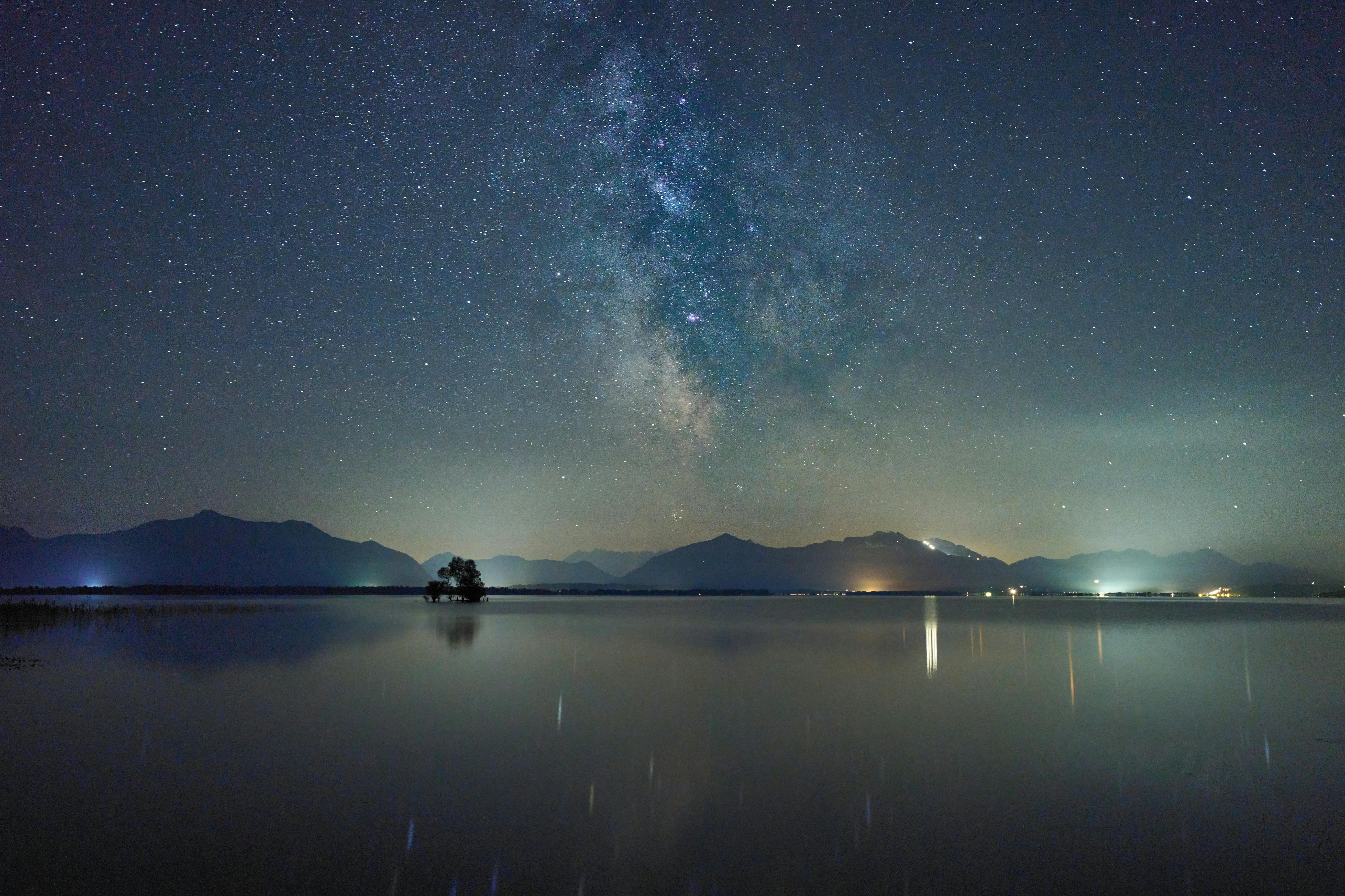 Beautiful Milky Way above Chiemsee Lake reflecting starlit sky and mountains at night.