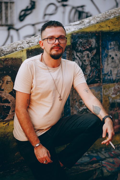 Free Stylish man with tattoos and glasses in an urban graffiti setting, exuding cool vibes. Stock Photo