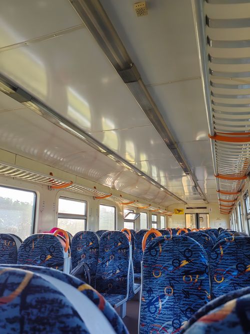 Free Sunlit interior of an empty modern train with patterned seats and overhead lighting. Stock Photo