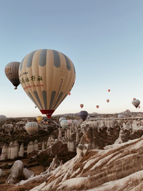 Free Scenic view of hot air balloons floating over Cappadocia's unique rock formations at sunrise. Stock Photo