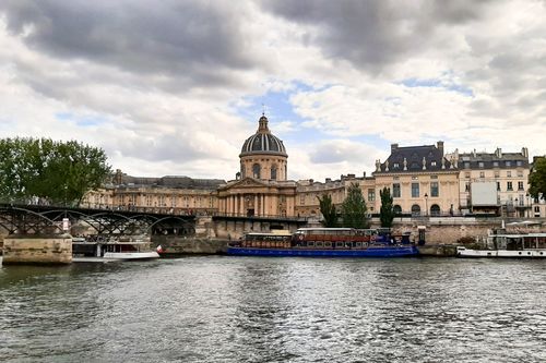 Free Scenic view of iconic Paris architecture along the Seine River on a cloudy day. Stock Photo