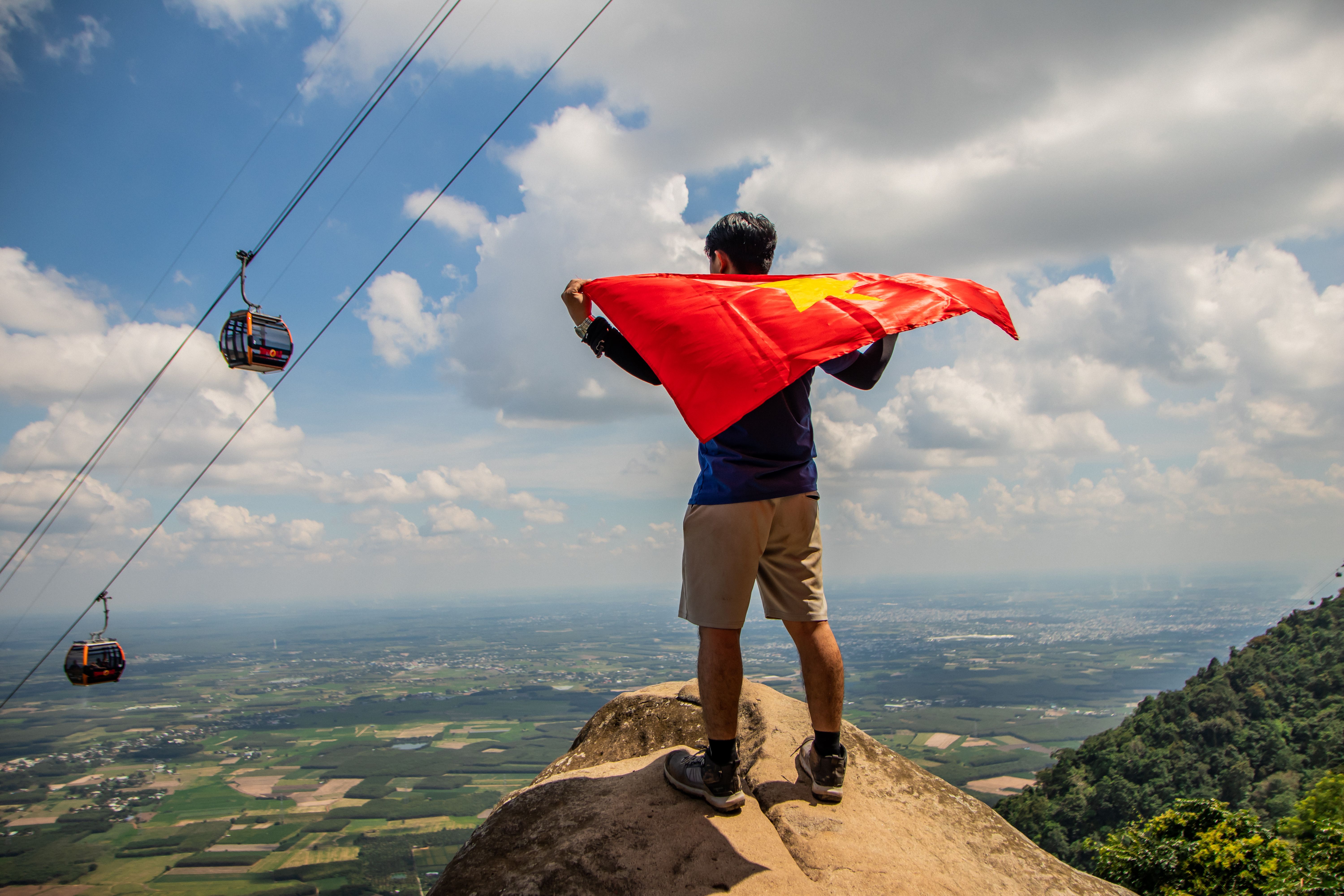 A man holding a flag on top of a mountain · Free Stock Photo
