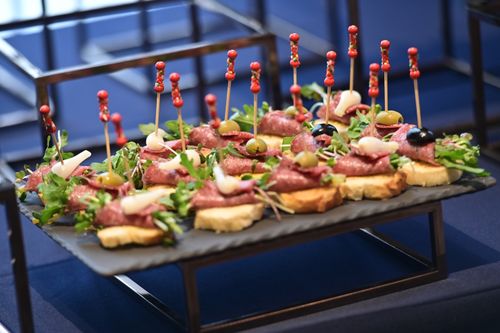 Free Delicious canapes with meat, olives, and greens on a stylish platter, perfect for events. Stock Photo