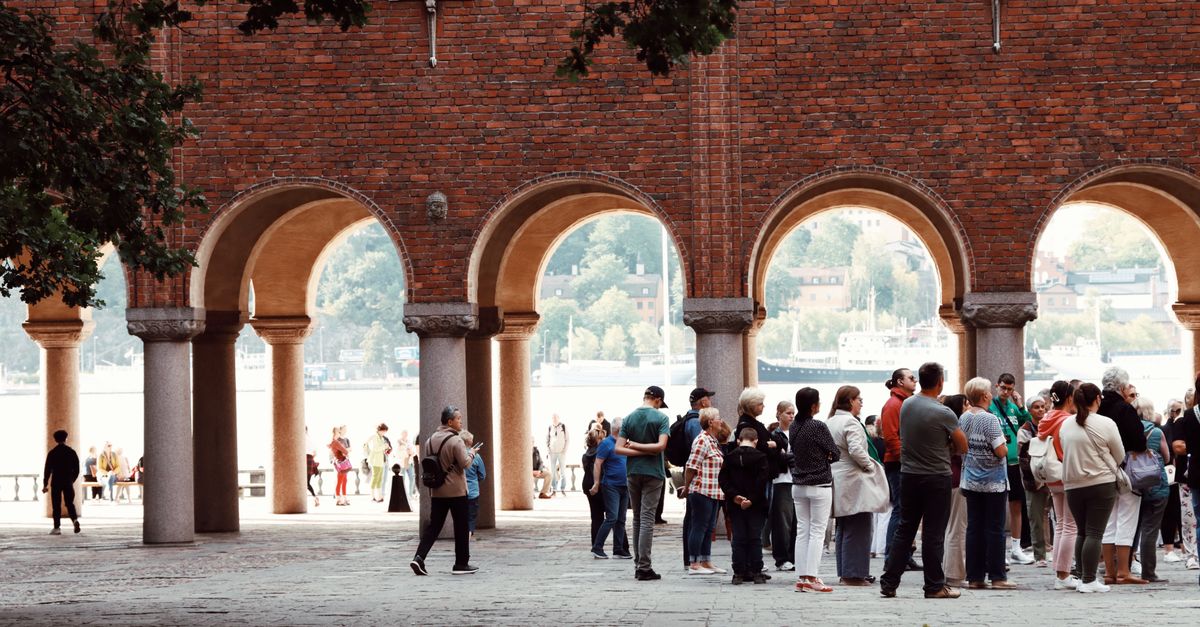 A group of tourists congregate under historic arches in Stockholm, Sweden.