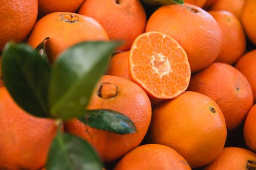A pile of oranges with one orange cut in half