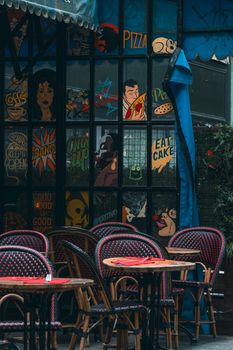 Charming outdoor café with colorful artwork and cozy seating, perfect for a relaxing urban setting.