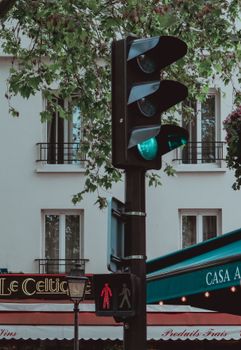 Street traffic light turning green at a city intersection with nearby cafe.
