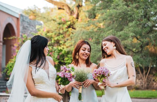 Three bridesmaids holding bouquets, smiling outdoors in a garden setting, Santiago de Querétaro.