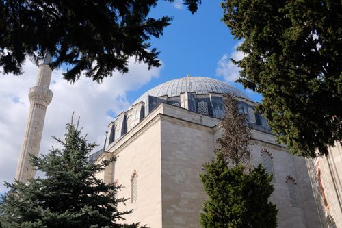 Free A stunning view of a dome and minaret amidst trees under a clear blue sky. Stock Photo