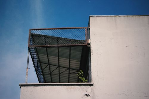 Free Minimalist view of a building's exterior with a metal roof and blue sky backdrop. Stock Photo