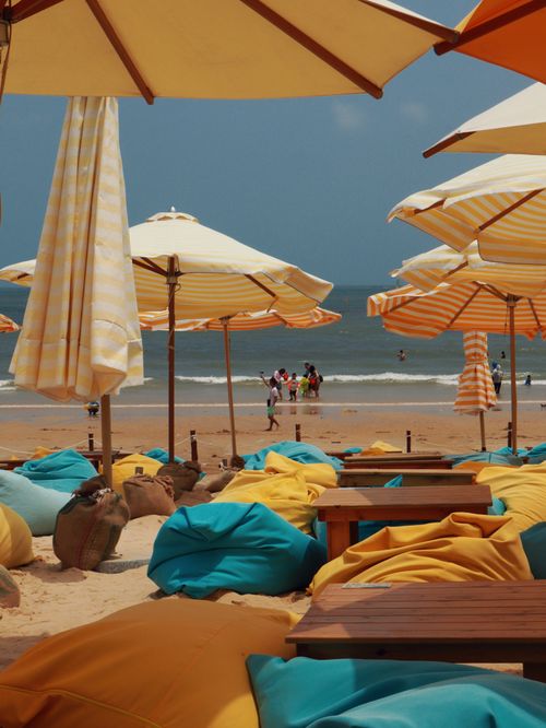 Free Vibrant beach setting with umbrellas and beanbag chairs on a sunny day. Stock Photo