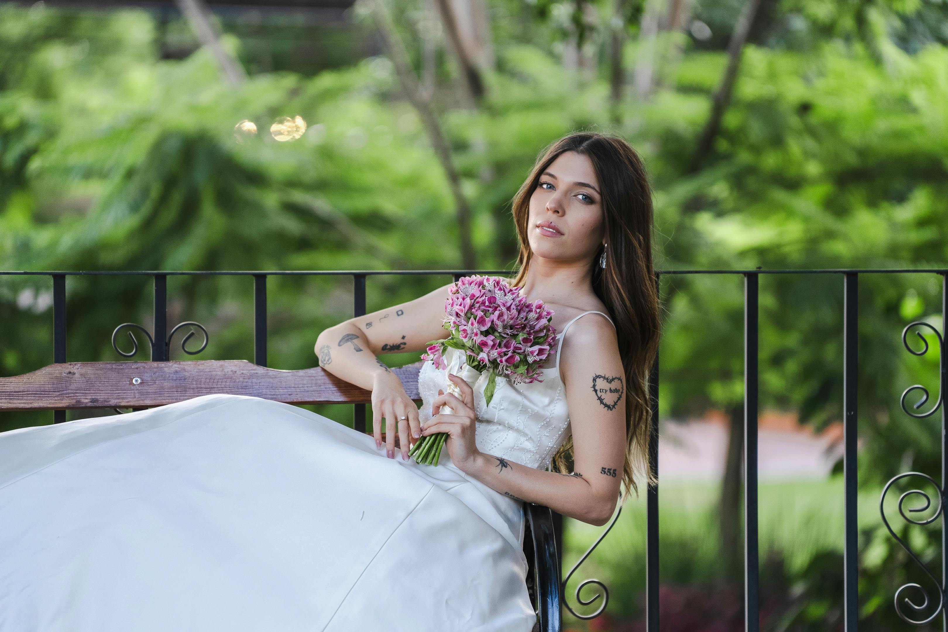 Elegant bride relaxing outdoors holding a bouquet of pink flowers, Santiago de Querétaro.