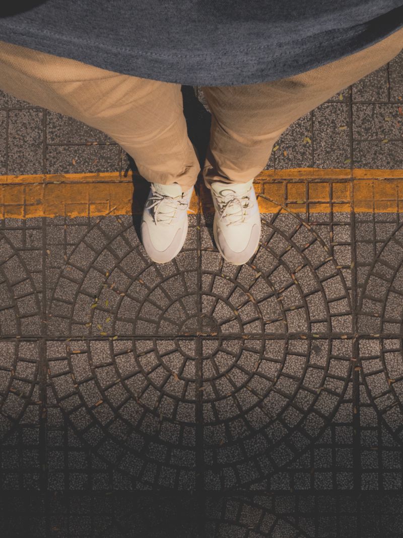 Top view of white sneakers on patterned pavement — photo by Alex Nguyen on Pexels