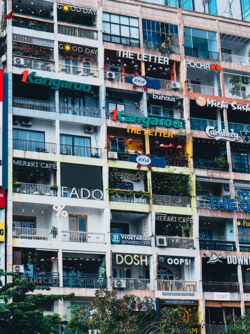 Free Colorful storefronts and cafes in a Saigon apartment building highlight urban Vietnamese culture. Stock Photo