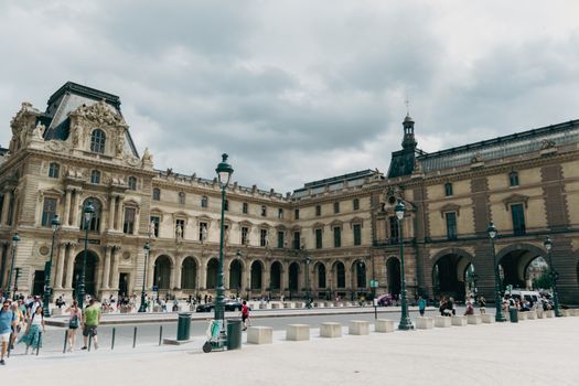 A historic view of Louvre Palace in Paris, capturing its stunning architecture and bustling square.