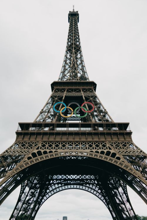 Free View of the Eiffel Tower adorned with Olympic rings, a symbol of Parisian heritage. Stock Photo