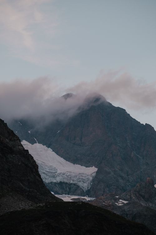 Free Dramatic mountain landscape with glacier and clouds at twilight, perfect for travel and nature themes. Stock Photo