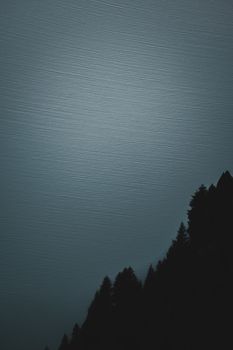 A tranquil mountain silhouette set against a textured dark sky, evoking mystery and solitude.