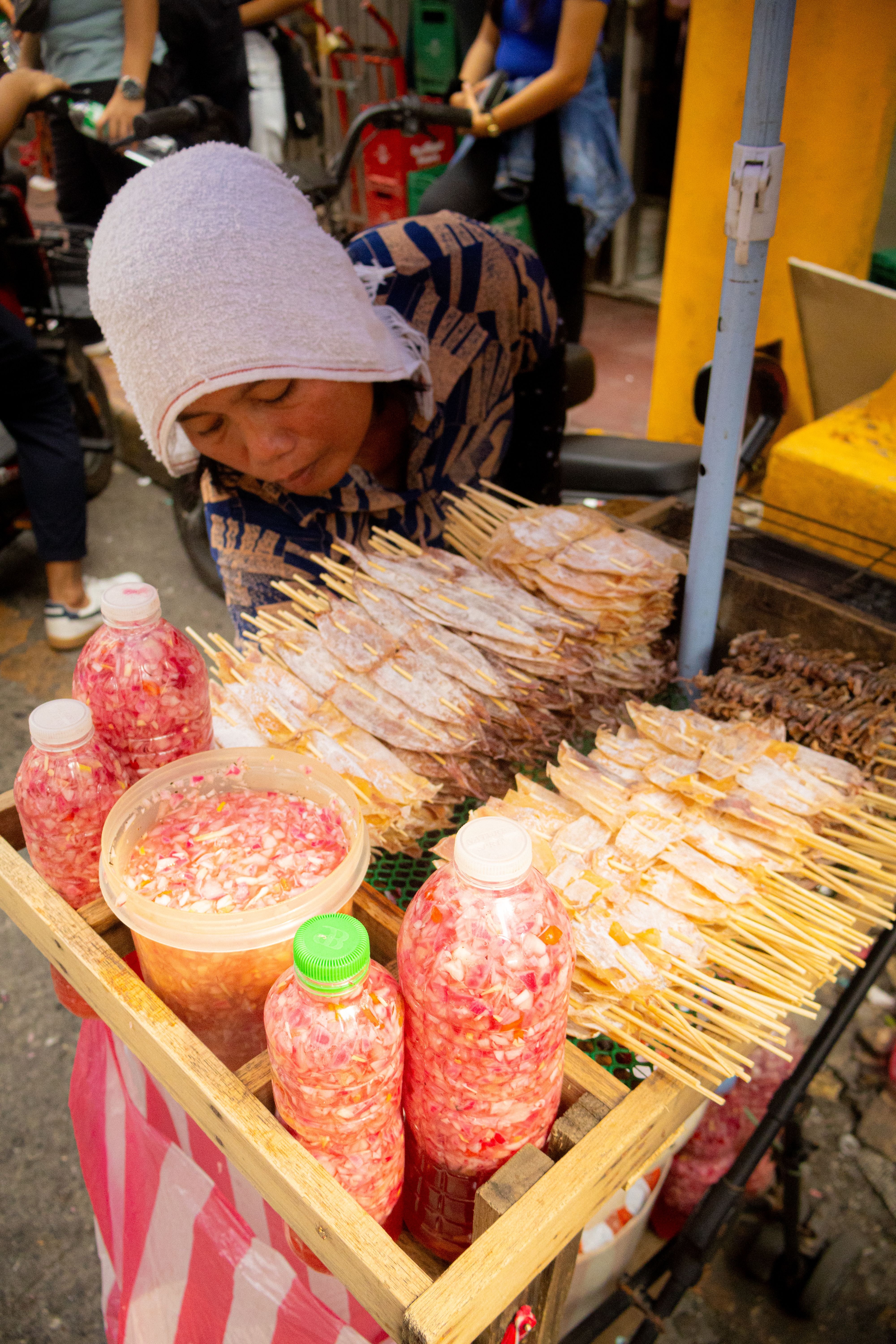 A busy street market vendor selling skewers and drinks at an outdoor festival.