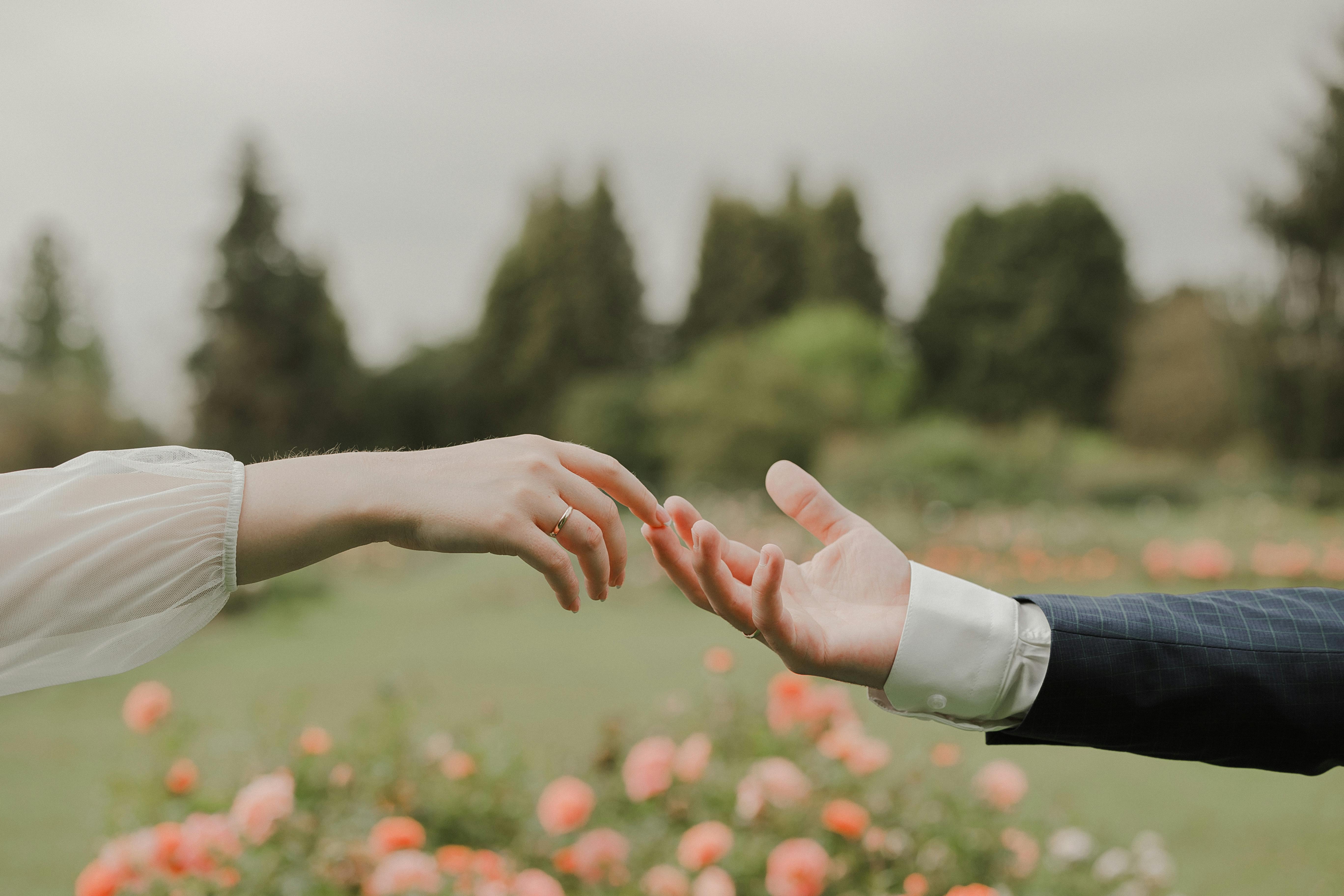 a couple holding hands in front of a flower garden