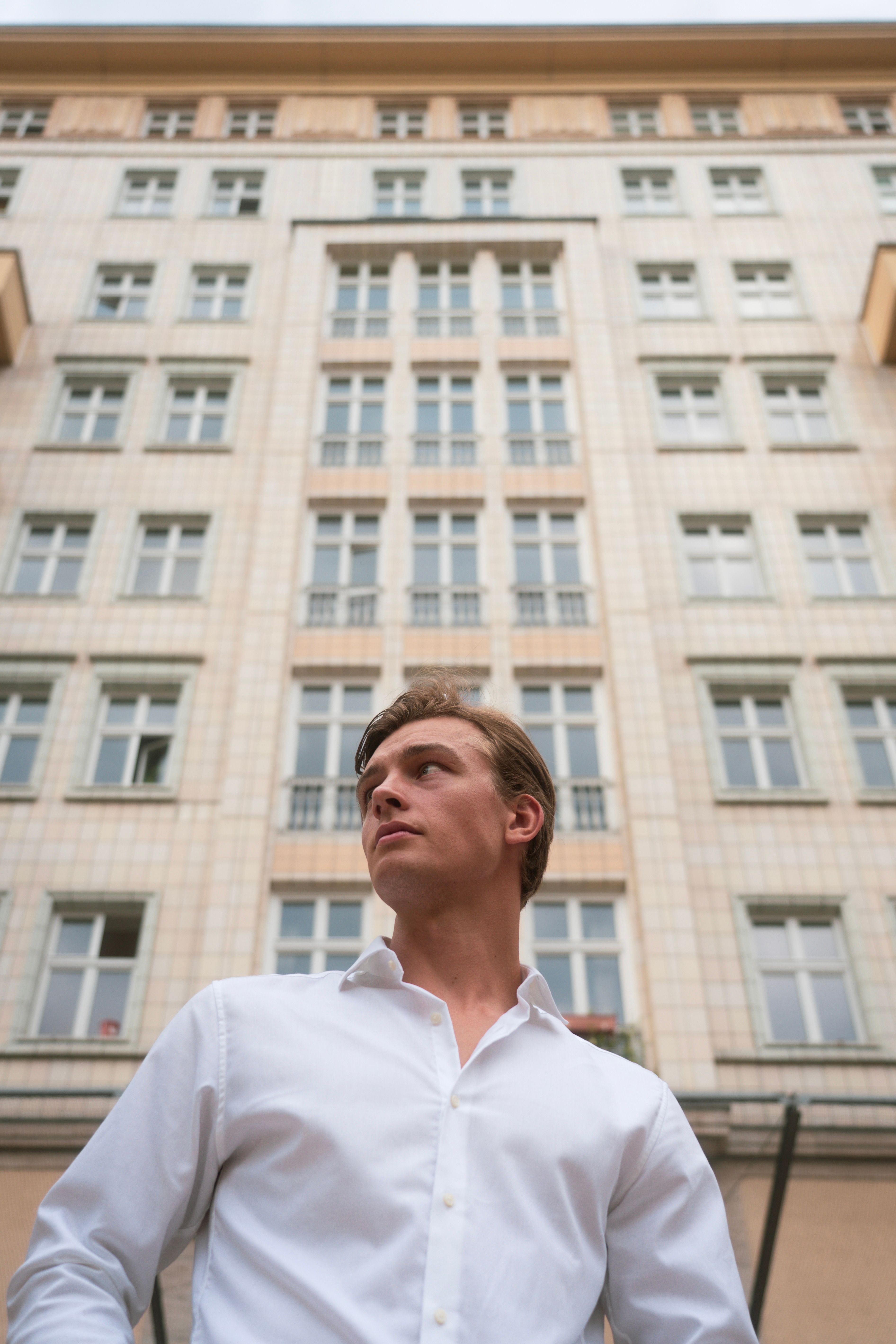 A man in a white shirt standing in front of a tall building · Free ...