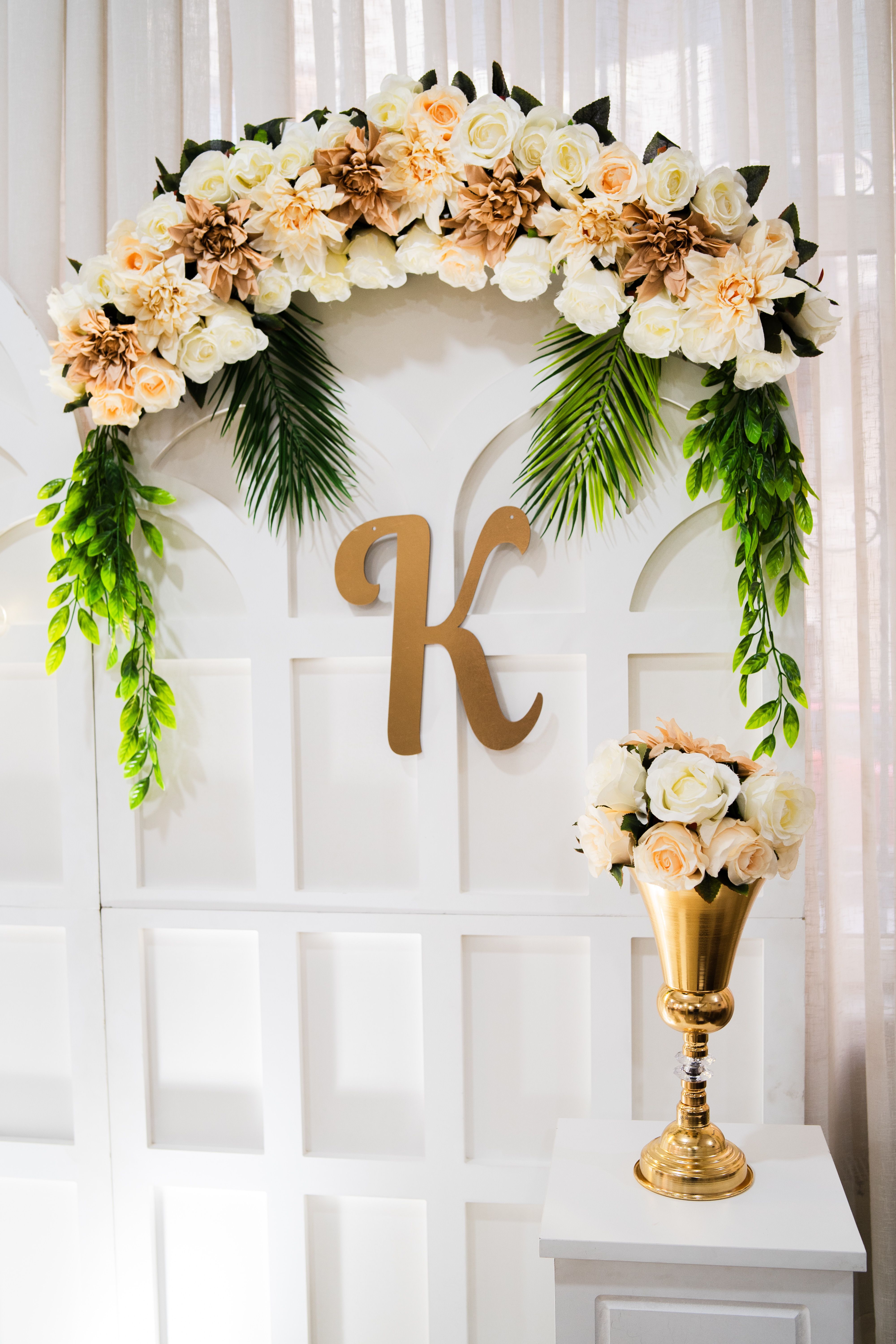 Stylish floral arrangement over a golden letter K, perfect for weddings and events.