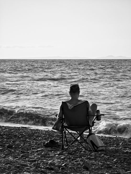 Free Black and white image of a person relaxing by the ocean, embodying tranquility and solitude. Stock Photo